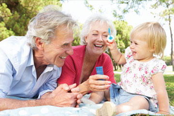 A little girl blowing bubbles with her grandparents. Links to Gifts from Retirement Plans